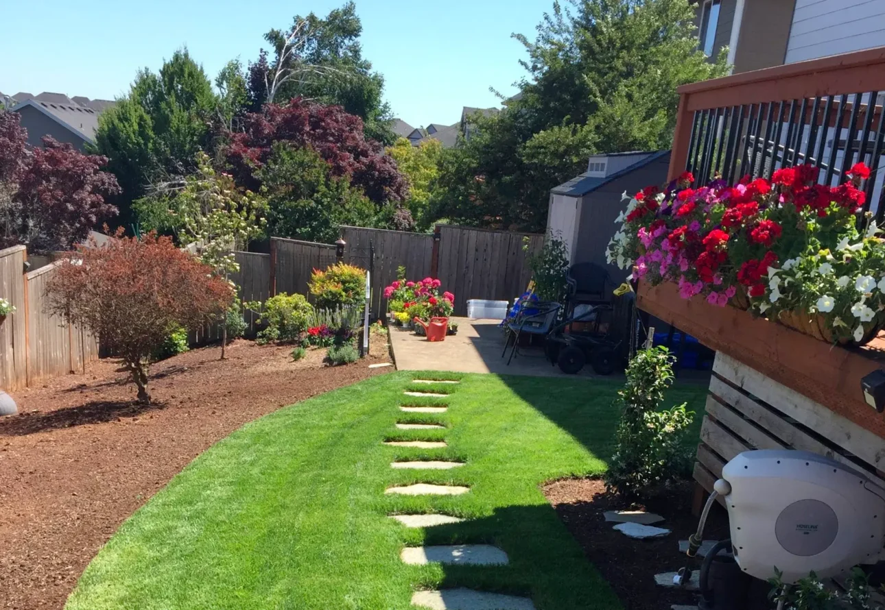 Professional residential landscaping featuring maintained lawn, flower garden, and decorative planters