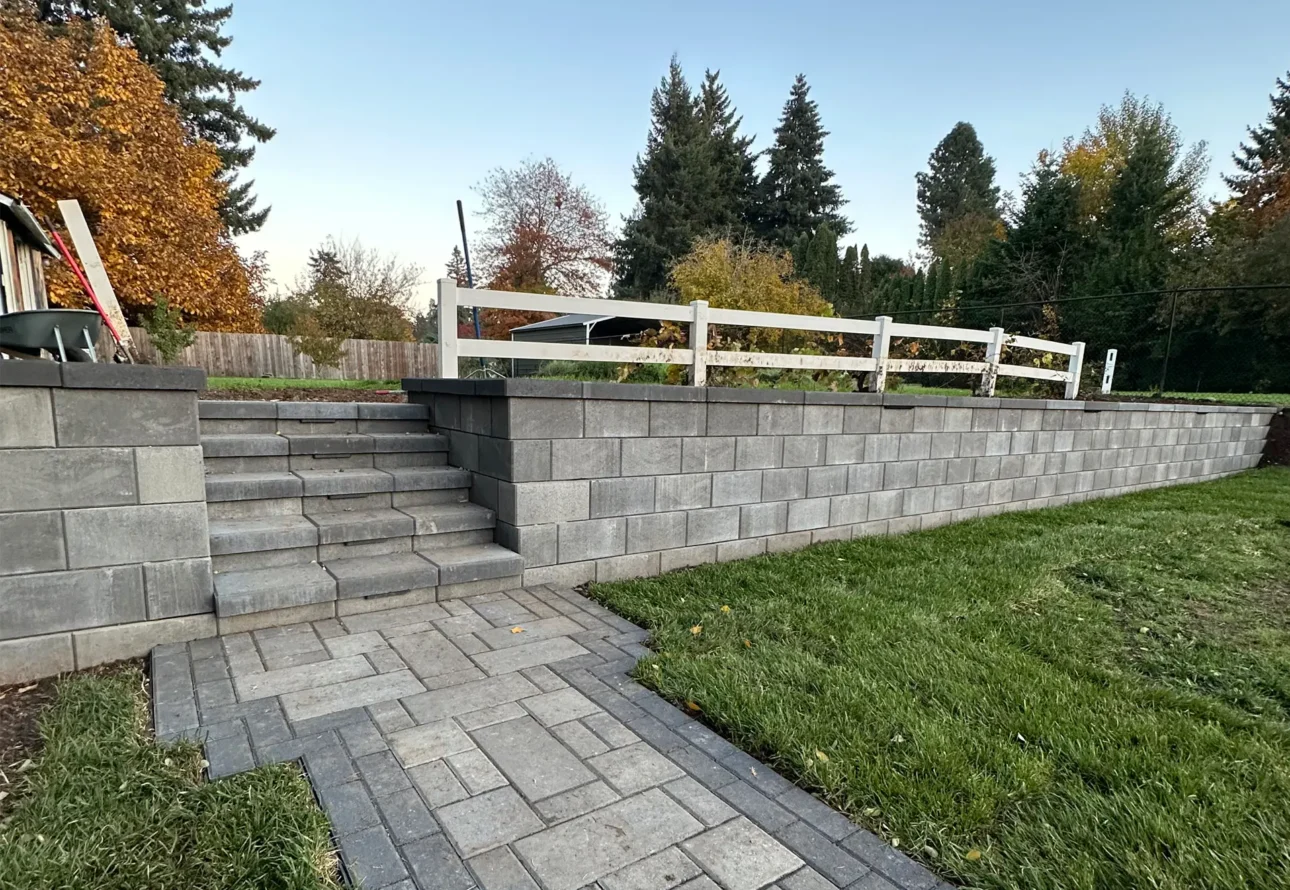 Professional retaining wall and paver step installation with elevated garden area and lawn