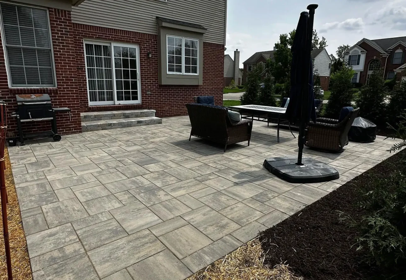Professional hardscape patio installation featuring concrete pavers and outdoor seating