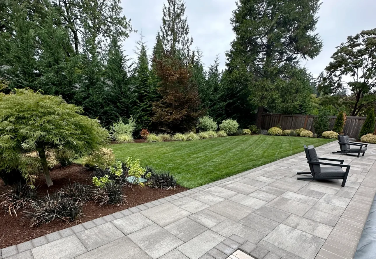 Modern paver patio with lounge chairs beside a freshly mowed lawn and professional landscaping