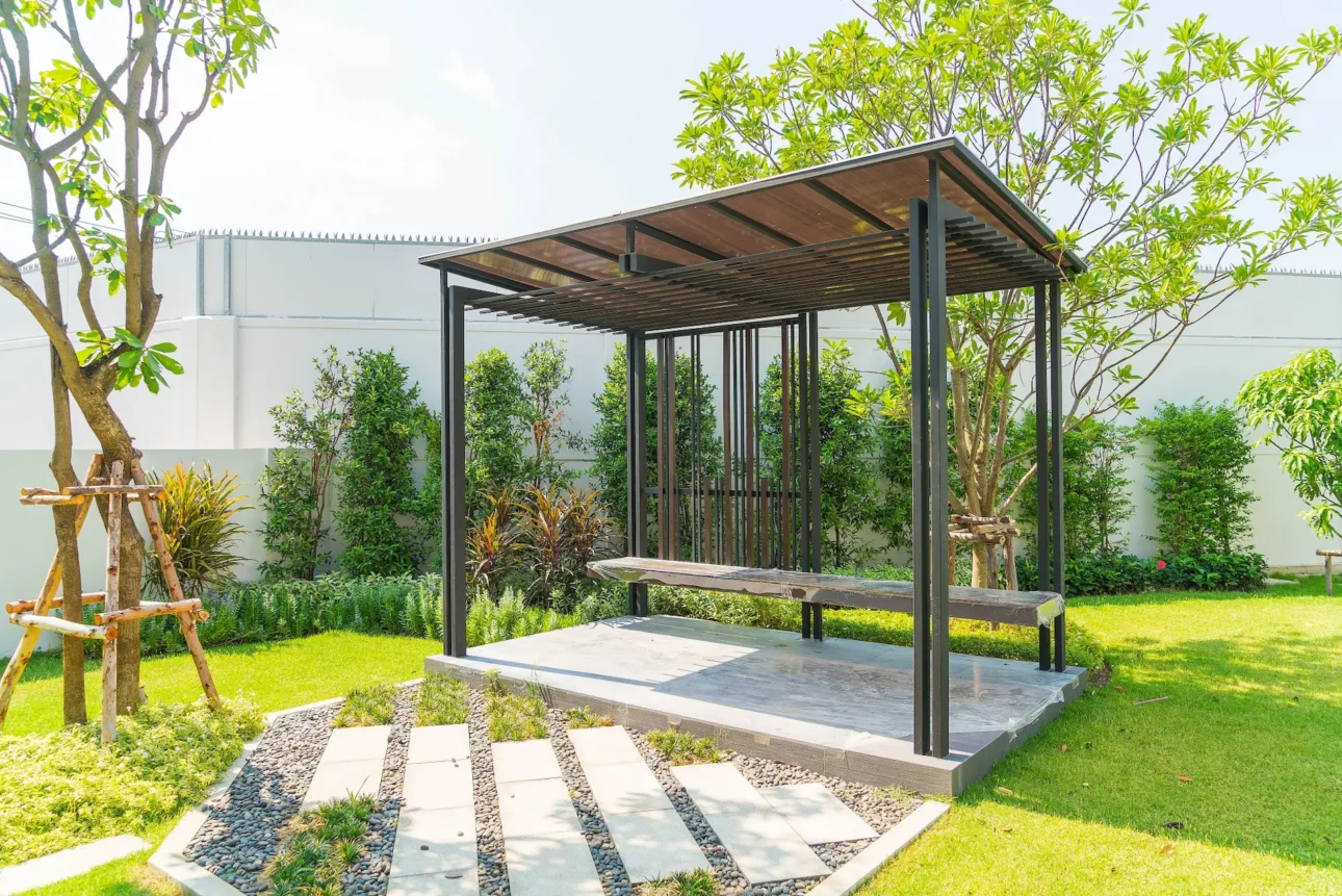 Modern garden pavilion with metal pergola, stone pathway, and landscaped greenery
